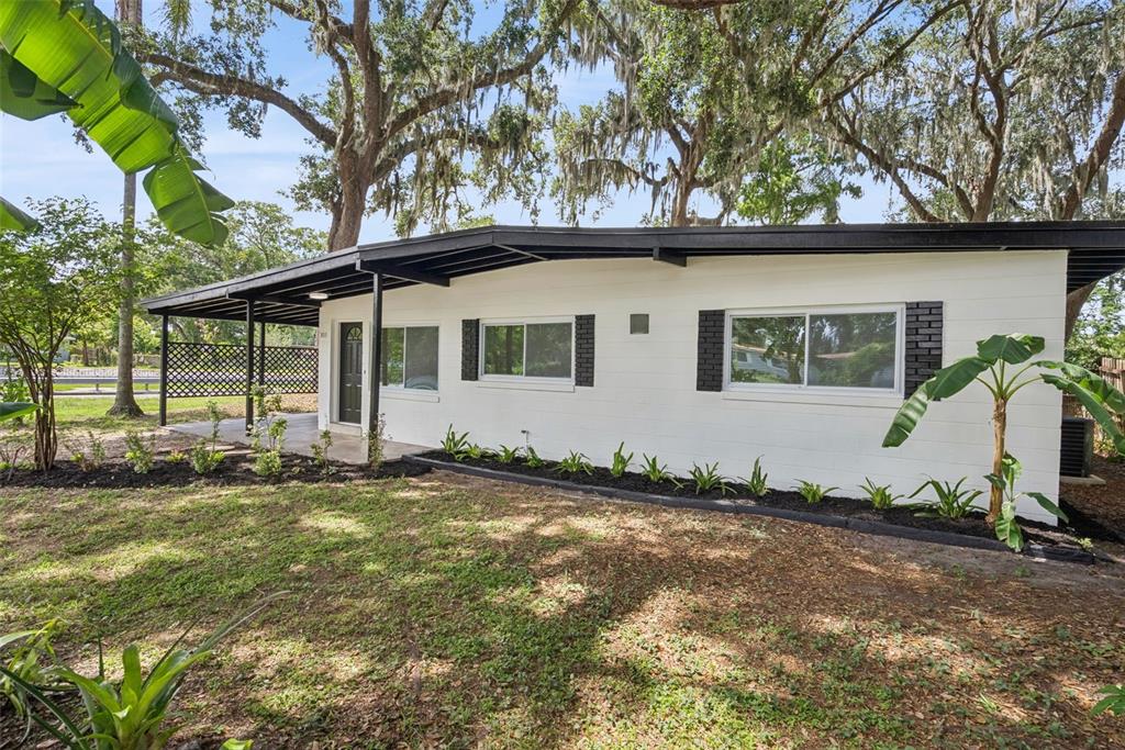 A white, single-story house with a black roof and trim sits behind a landscaped bed — 3013 KELVINGTON DRIVE, ORLANDO, FL
