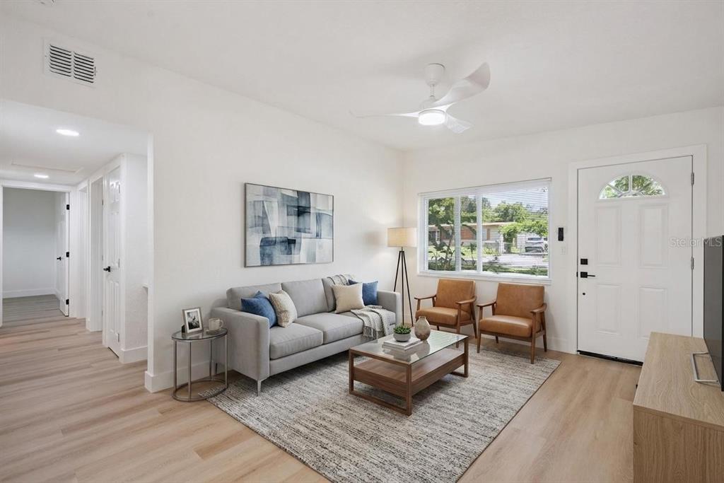A living room features light wood flooring, a grey sofa, two leather chairs, and white walls — 3013 KELVINGTON DRIVE, ORLANDO, FL