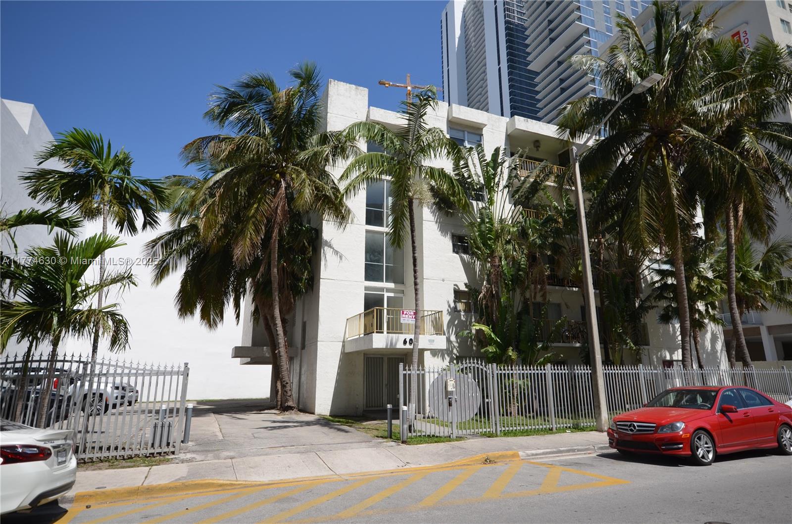A multi-story white apartment building with palm trees and a red car parked in front — 601 NE 22nd St, Miami FL 33137, MIAMI, FL