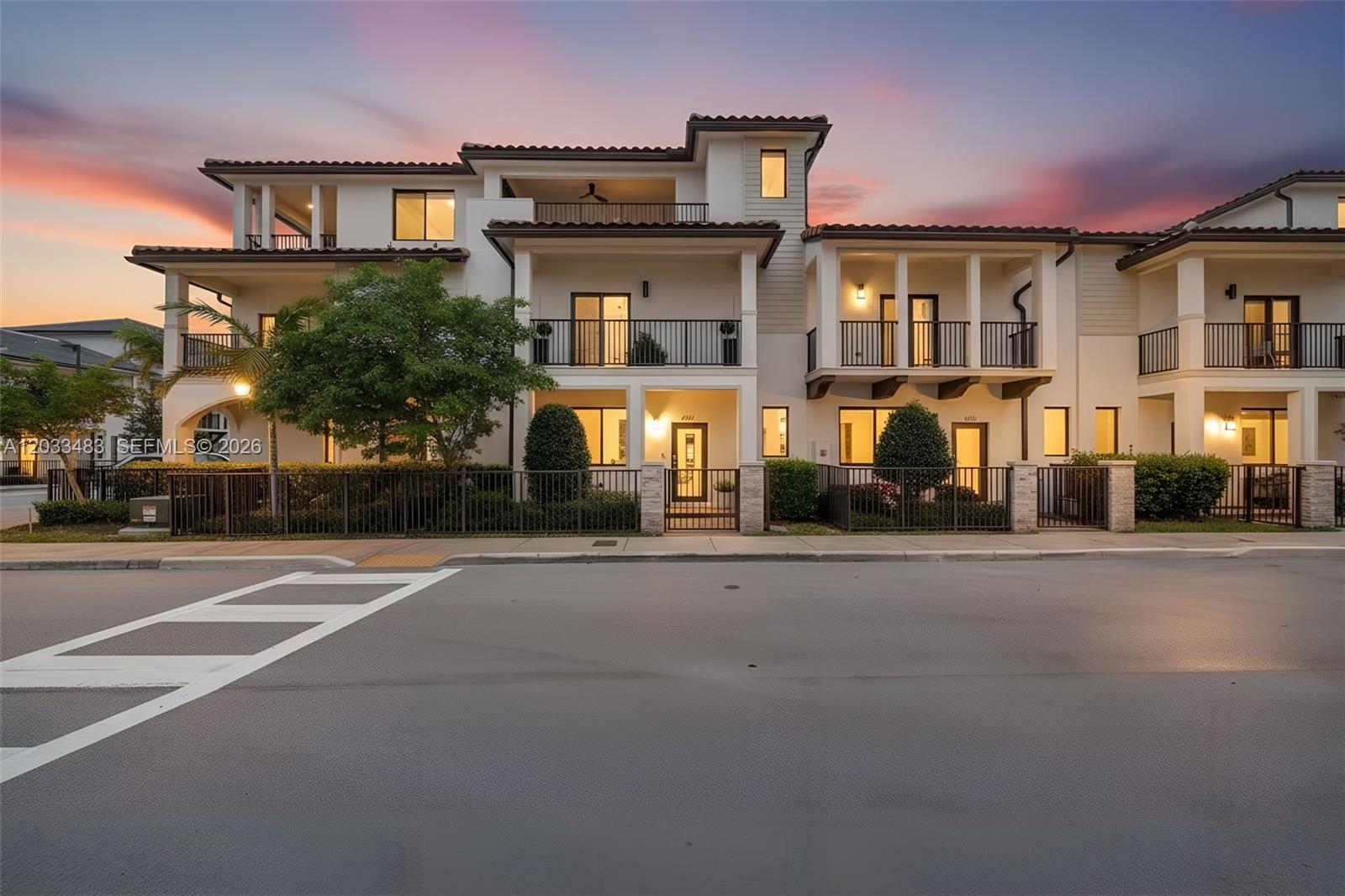 A multi-story residential building with balconies and a gated front yard at sunset — 4256 NW 83rd Ave, Doral FL 33166, DORAL, FL