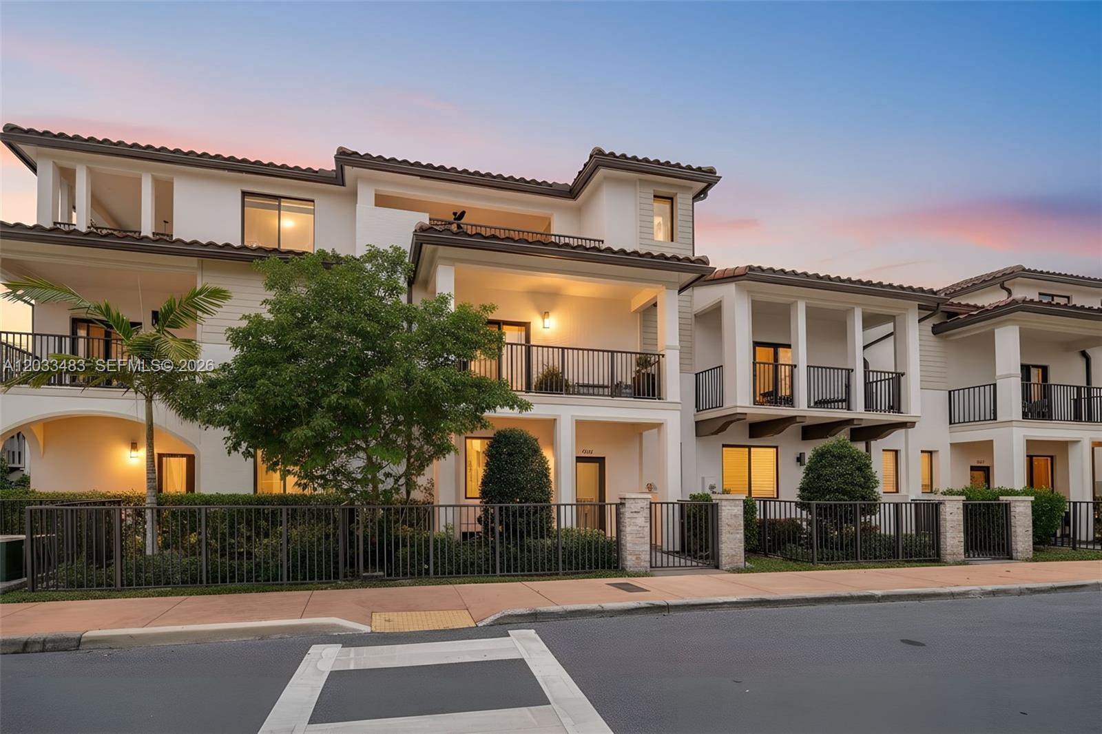 A multi-story townhouse exterior features balconies, a fenced front yard, and a paved sidewalk — 4256 NW 83rd Ave, Doral FL 33166, DORAL, FL