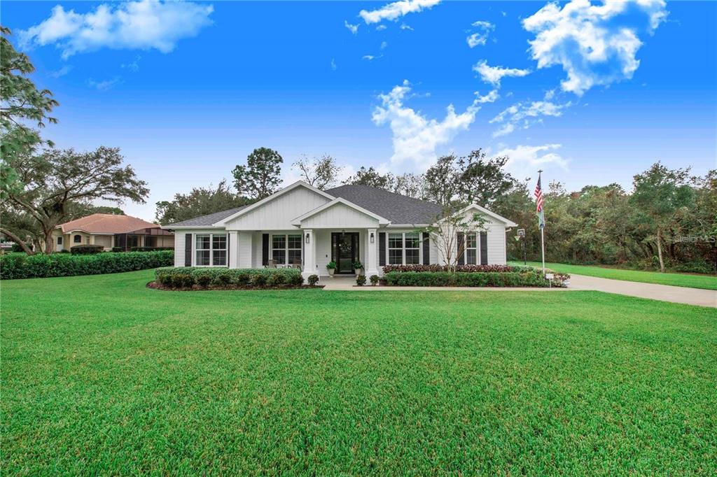A white single-story house with black shutters and a large front lawn under a blue sky — 2997 SEQUOYAH DRIVE, HAINES CITY, FL