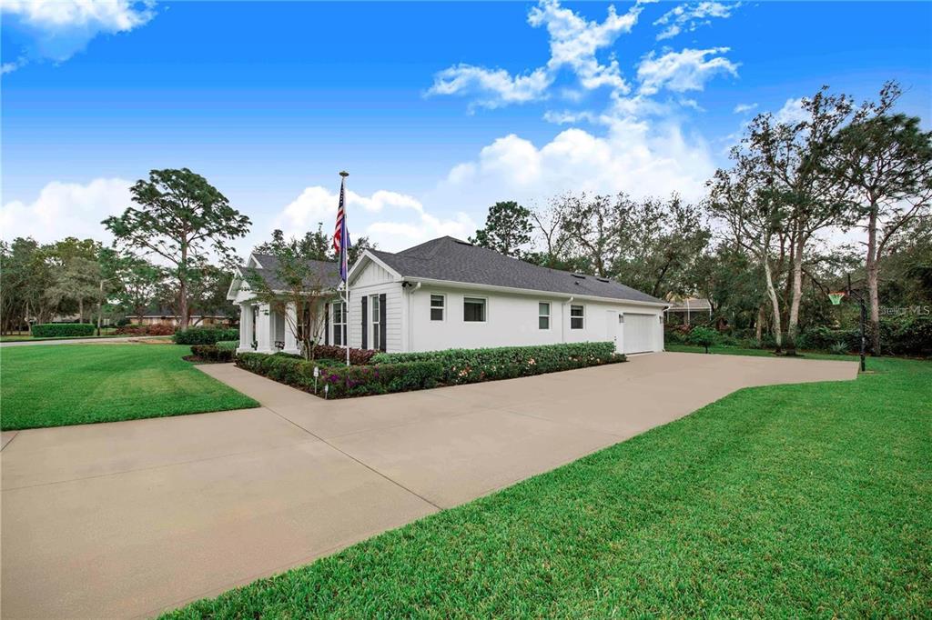 A white single-story house with a large concrete driveway and an American flag — 2997 SEQUOYAH DRIVE, HAINES CITY, FL
