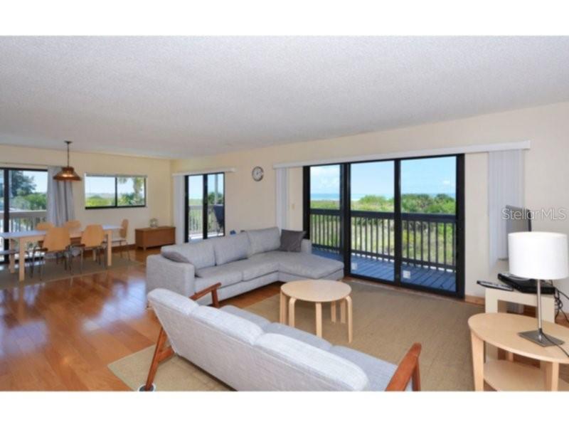 A living room features a sectional sofa, a dining area, and a large sliding glass door — 460 BEACH ROAD UNIT A1, SARASOTA, FL