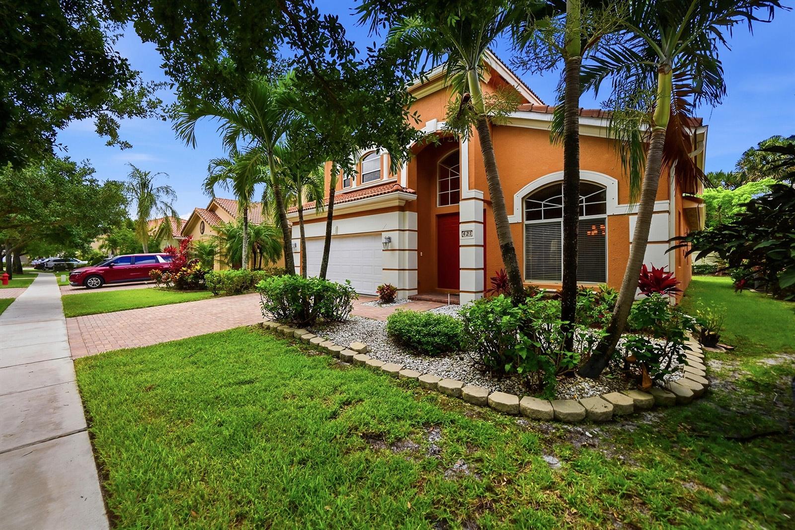 A two-story orange stucco house with a red front door and a paved driveway — 421 Gazetta Way, West Palm Beach FL 33413, WEST PALM BEACH, FL