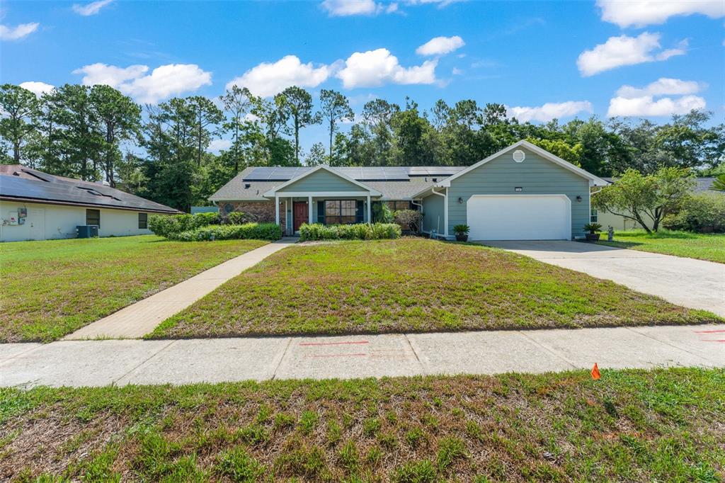 A single-story house with a green exterior, a two-car garage, and solar panels on the roof — 1341 S RIDGE LAKE CIRCLE, LONGWOOD, FL