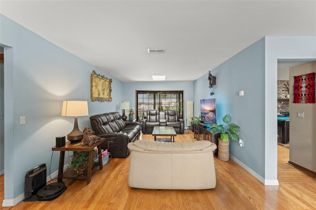 A living room features light blue walls, hardwood floors, leather furniture, and a sliding glass door — 1341 S RIDGE LAKE CIRCLE, LONGWOOD, FL