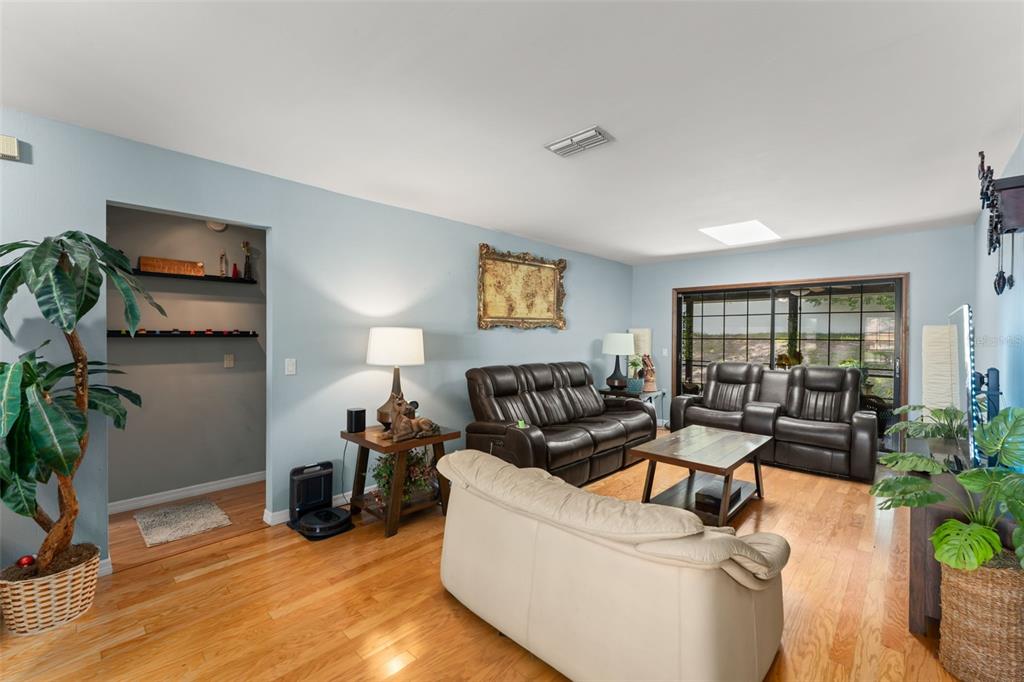 A living room features hardwood floors, light blue walls, and three leather sofas — 1341 S RIDGE LAKE CIRCLE, LONGWOOD, FL