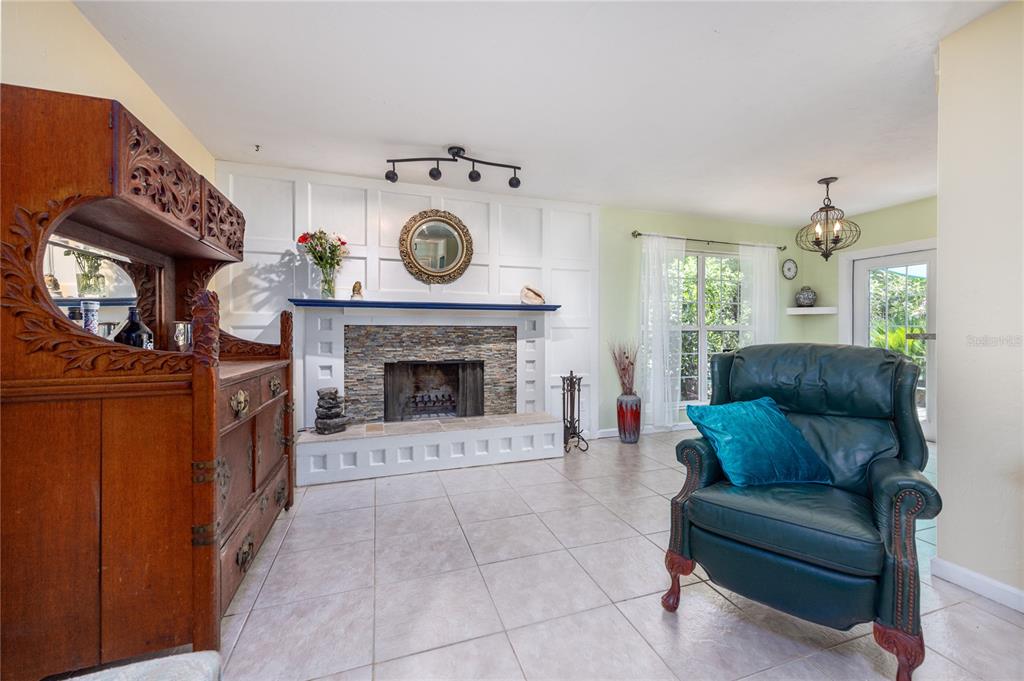 A living room features a stone fireplace, white paneled wall, tile flooring, and a leather armchair — 11212 SW 86TH PLACE, GAINESVILLE, FL