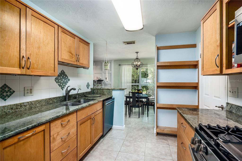 A kitchen with wood cabinets, granite countertops, and an open view into a dining area — 11212 SW 86TH PLACE, GAINESVILLE, FL