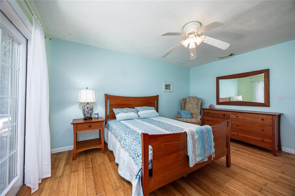 A bedroom with light blue walls, a wooden bed frame, and hardwood flooring — 11212 SW 86TH PLACE, GAINESVILLE, FL