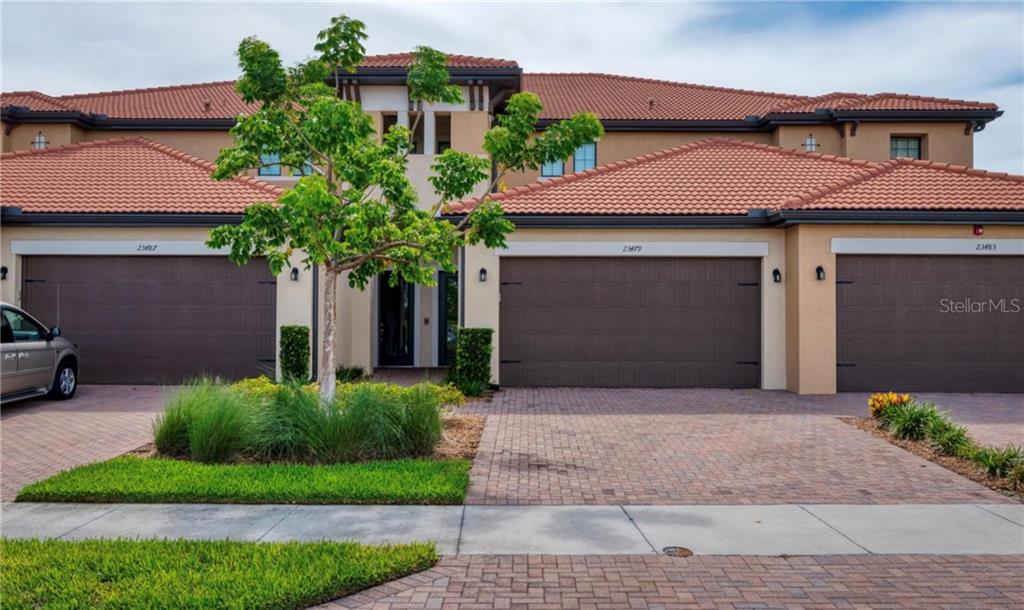 A multi-unit residential building with brown garage doors and a tiled roof — 23479 AWABUKI DRIVE UNIT 202, VENICE, FL
