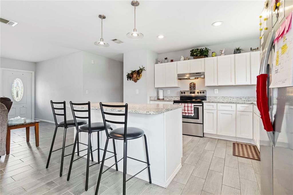 A kitchen features white cabinets, granite countertops, stainless steel appliances, and a breakfast bar — 20550 EDGEWATER DRIVE, PORT CHARLOTTE, FL