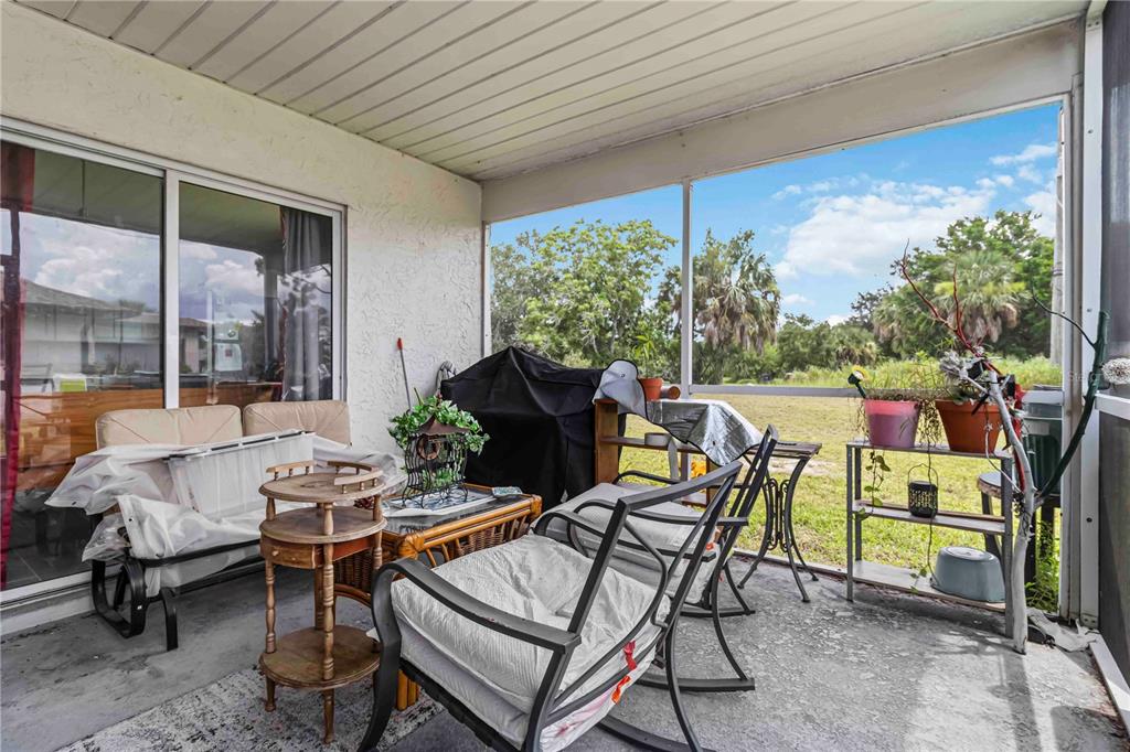 A screened-in patio features concrete flooring, outdoor furniture, and a view of a grassy yard — 20550 EDGEWATER DRIVE, PORT CHARLOTTE, FL