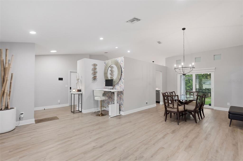 A bright, open-concept dining and office area features light wood flooring and a floral accent wall — 9693 58TH STREET N, PINELLAS PARK, FL