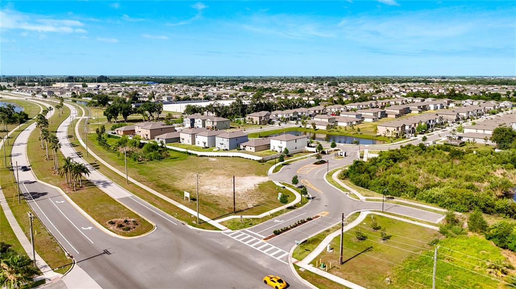 An aerial view shows a suburban neighborhood with houses, roads, and a vacant lot — 2282 JUNGLE DRIVE, RUSKIN, FL
