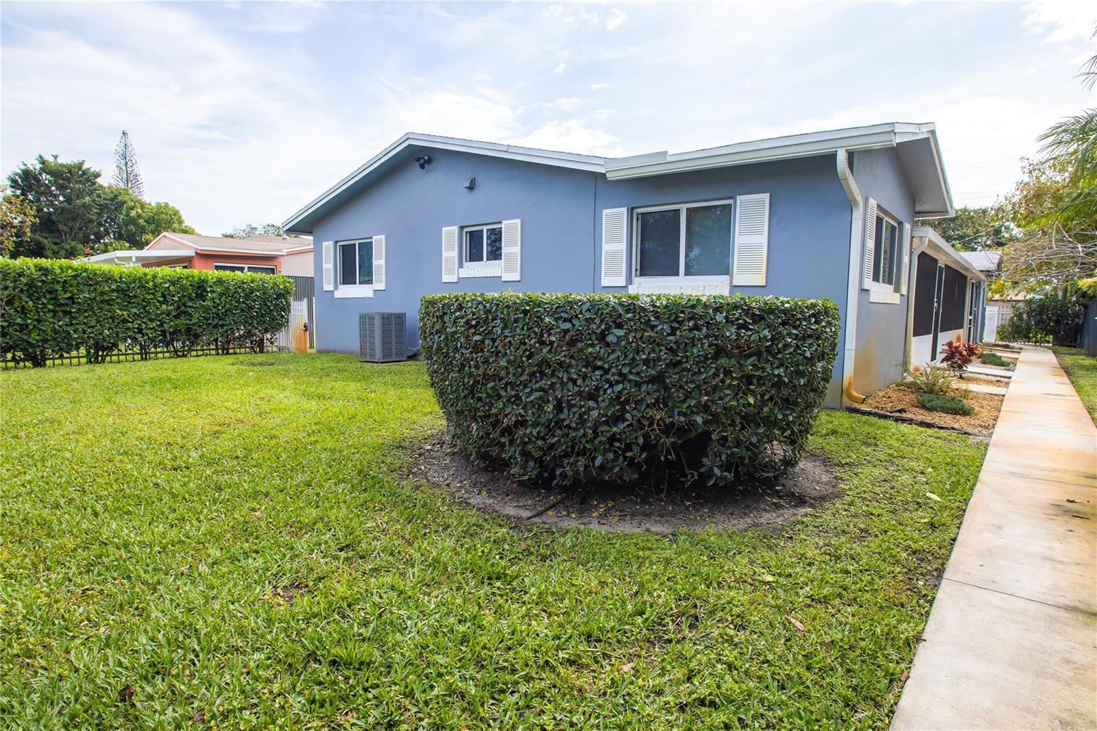 A blue house exterior features a large manicured hedge, a lawn, and a concrete walkway — 2432 Sherman Street, Hollywood FL 33020, HOLLYWOOD, FL