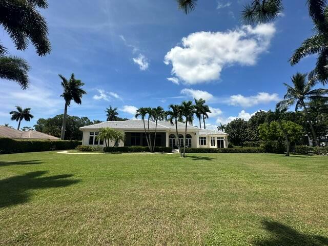 A single-story house with a large lawn and palm trees under a blue sky — 645 Atlantis Estates Way, Atlantis FL 33462, ATLANTIS, FL