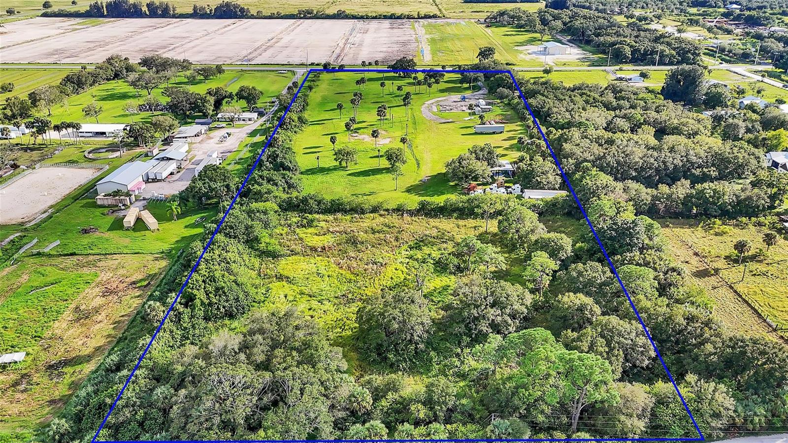 An aerial view shows a large, rectangular plot of land with trees and open grass — 15150 Orange Avenue, Fort Pierce FL 34945, FORT PIERCE, FL