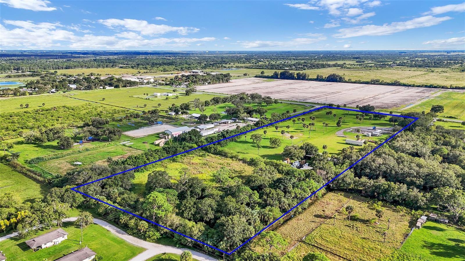 An aerial view shows a large, rectangular plot of land with trees and open fields — 15150 Orange Avenue, Fort Pierce FL 34945, FORT PIERCE, FL