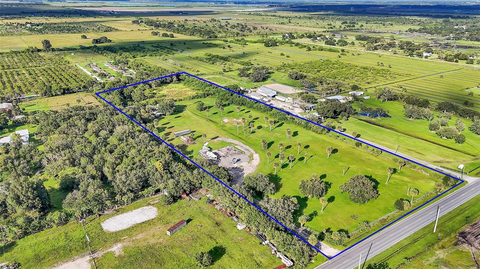 An aerial view shows a large, rectangular grassy lot bordered by trees and a road — 15150 Orange Avenue, Fort Pierce FL 34945, FORT PIERCE, FL