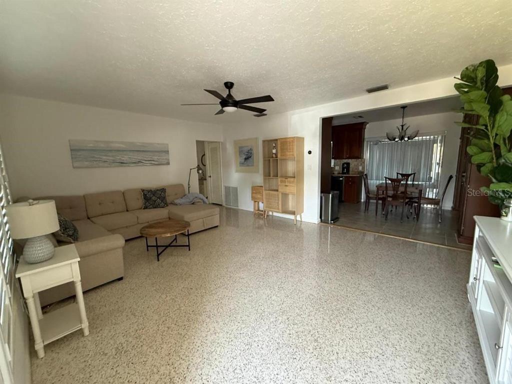 A living room with a beige sectional sofa, terrazzo flooring, and an adjacent dining area — 6015 CARLTON AVENUE, SARASOTA, FL