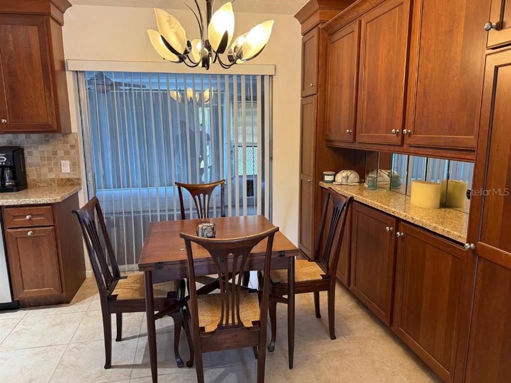 A dining area features a wooden table, four chairs, a chandelier, and cherry wood cabinetry — 6015 CARLTON AVENUE, SARASOTA, FL