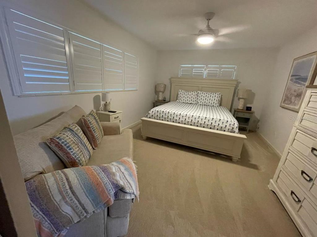A bedroom features a bed, a sofa, a dresser, and plantation shutters on the windows — 6015 CARLTON AVENUE, SARASOTA, FL