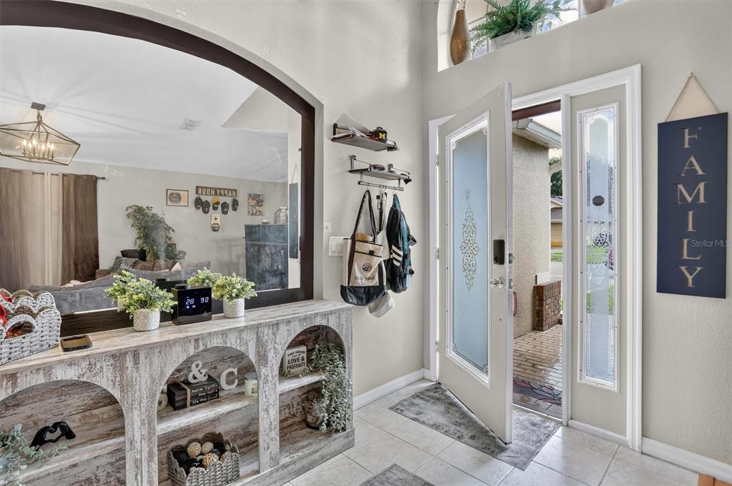 An entryway features a rustic console table, a large arched mirror, and a glass-paneled door — 19654 GLEN ELM WAY, ORLANDO, FL