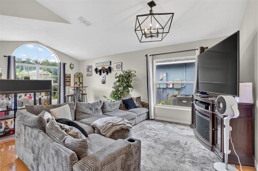 A living room features a large gray sectional sofa, a television on a stand, and a chandelier — 19654 GLEN ELM WAY, ORLANDO, FL