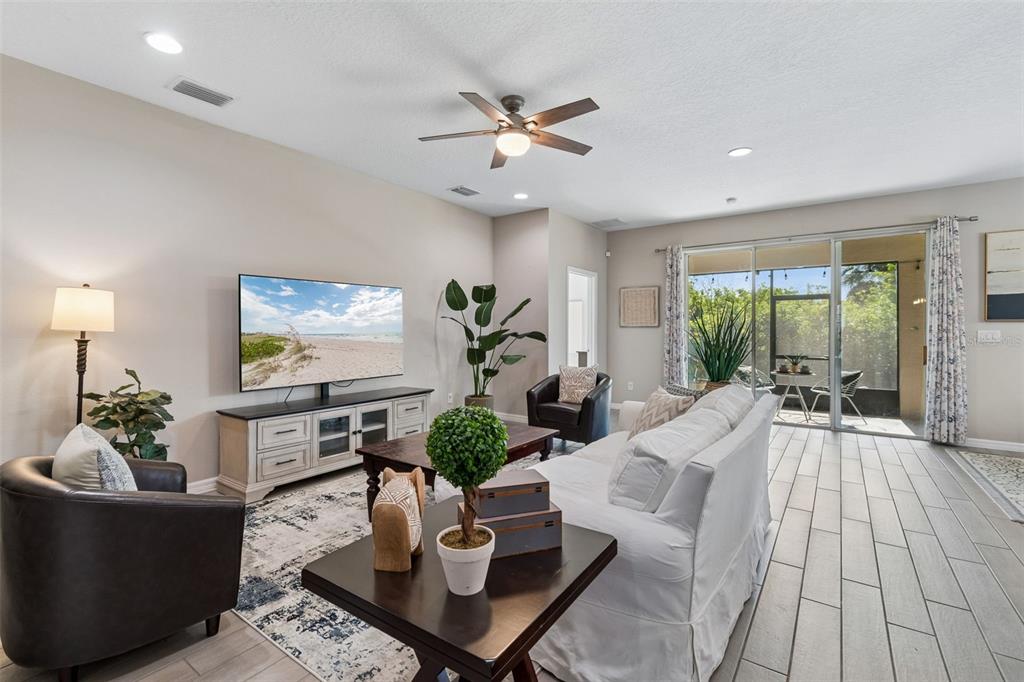 A living room features a white sofa, two dark armchairs, a television, and tile flooring — 12507 CANDLEBERRY CIRCLE, TAMPA, FL
