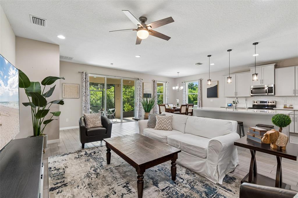 An open-concept living room and kitchen featuring a white sofa, wood coffee table, and patio — 12507 CANDLEBERRY CIRCLE, TAMPA, FL