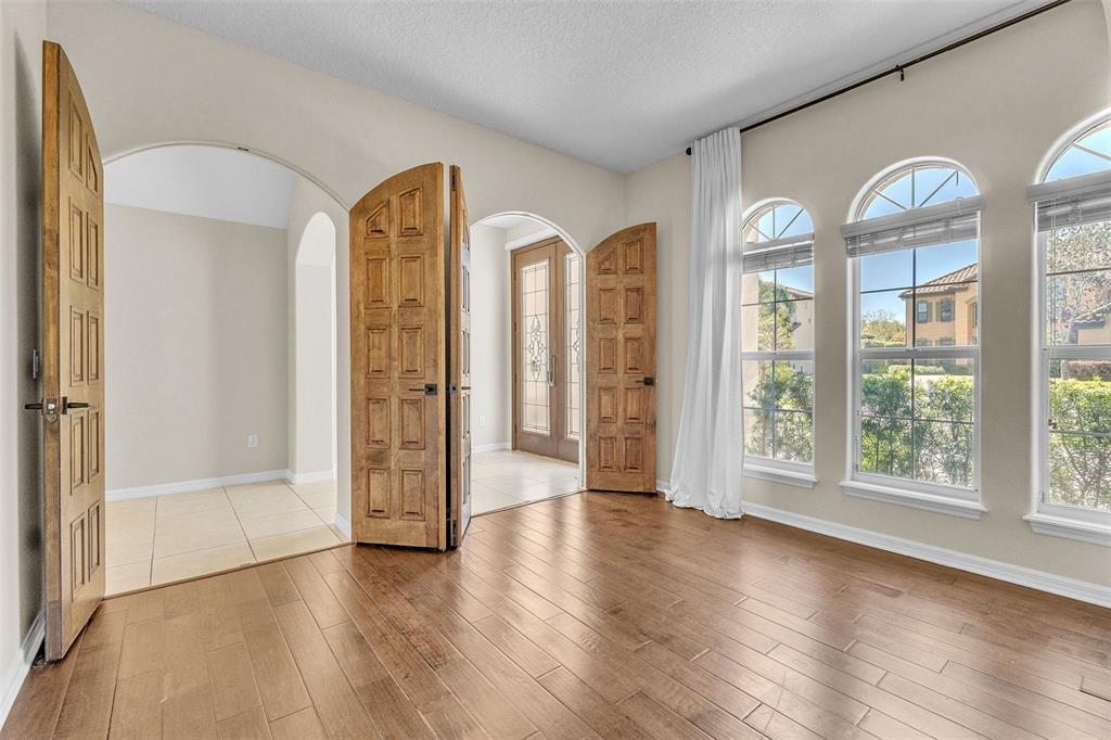 A room with hardwood floors, arched doorways, wooden double doors, and three large windows — 4617 PATRICIA ANN COURT, ORLANDO, FL
