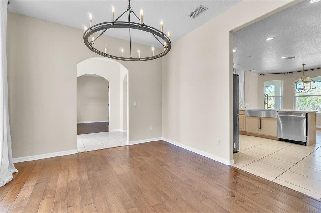 A dining area with wood flooring and a large chandelier connects to a kitchen — 4617 PATRICIA ANN COURT, ORLANDO, FL