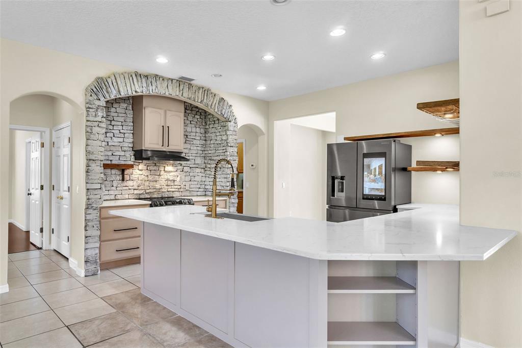 A kitchen features a stone-arched stove alcove, white quartz countertops, and a gray island — 4617 PATRICIA ANN COURT, ORLANDO, FL