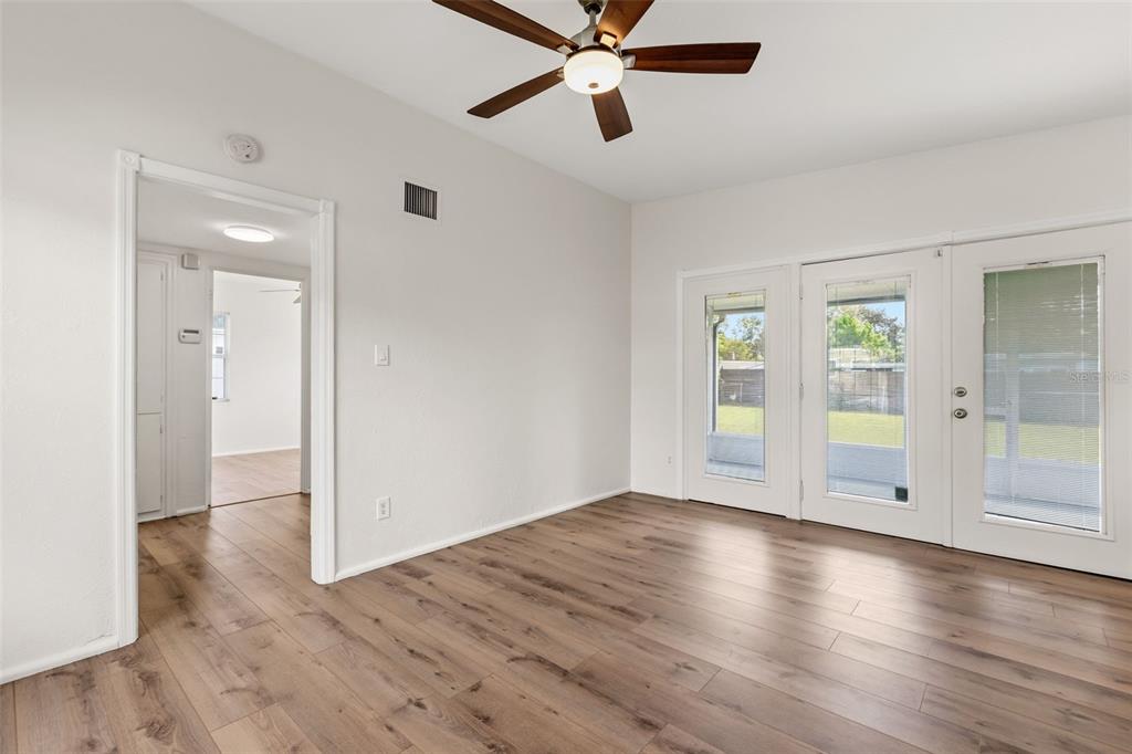 An empty room features light wood-look flooring, a ceiling fan, and glass doors to outside — 139 S ALDER DRIVE, ORLANDO, FL