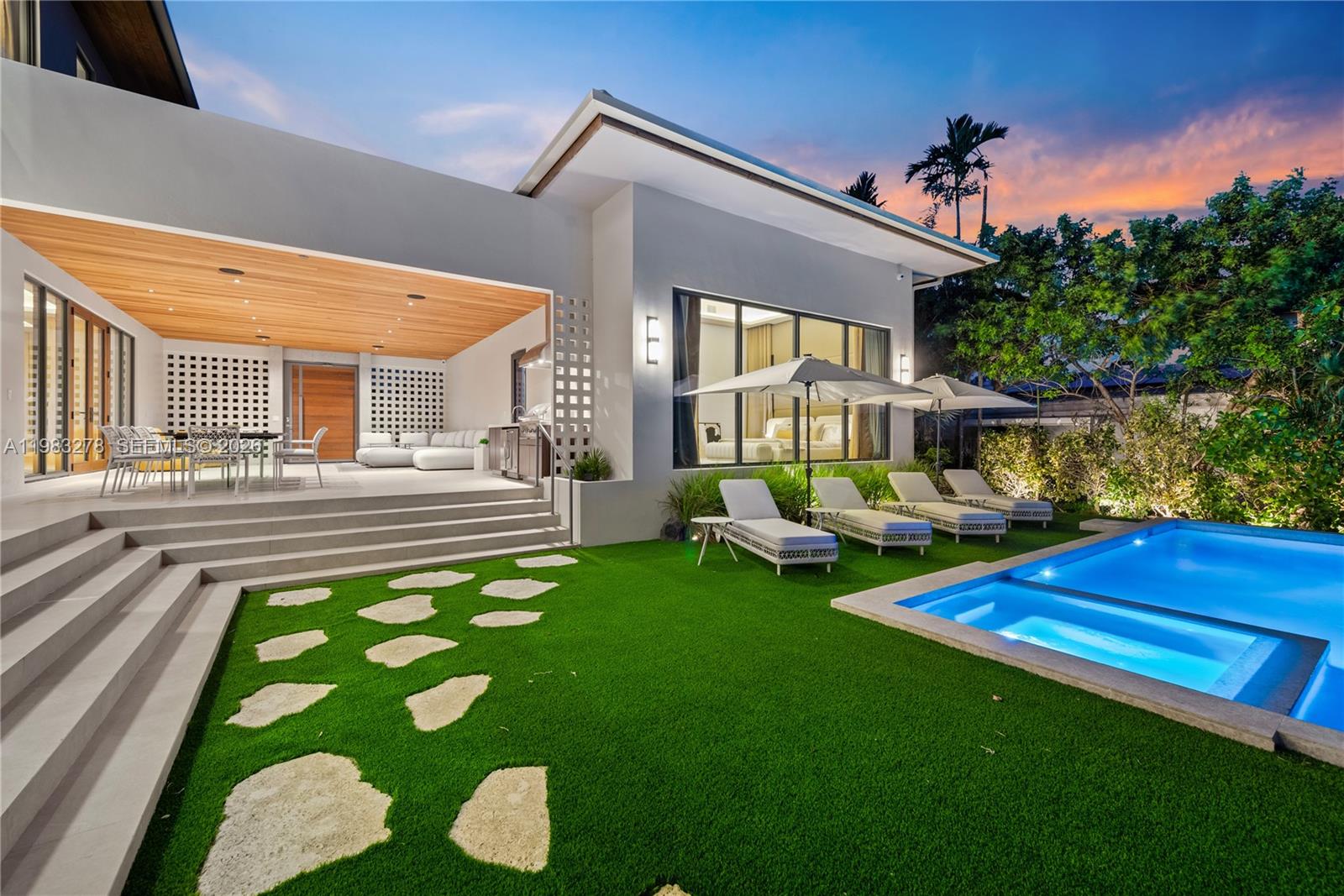 A modern house exterior features a covered patio, artificial turf lawn, and a swimming pool — 1200 NE 87th St, Miami FL 33138, MIAMI, FL