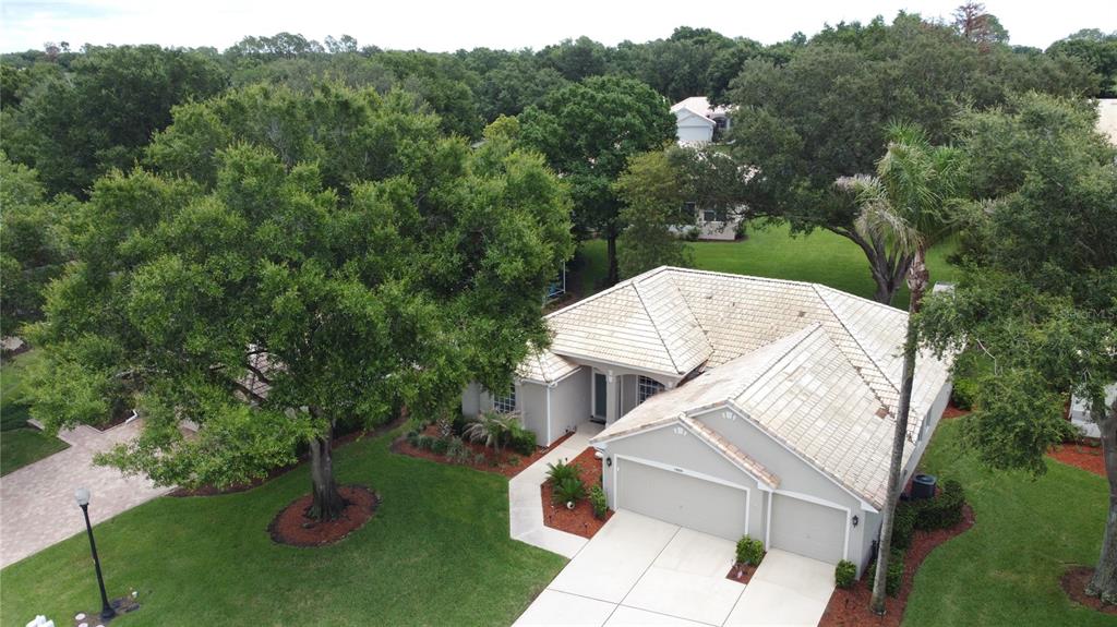 An aerial view shows a single-story house with a light-colored roof and a two-car garage — 2112 SAINT IVES COURT, CLERMONT, FL