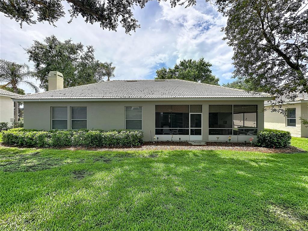 The rear exterior of a single-story house features a screened-in porch and a grassy lawn — 2112 SAINT IVES COURT, CLERMONT, FL