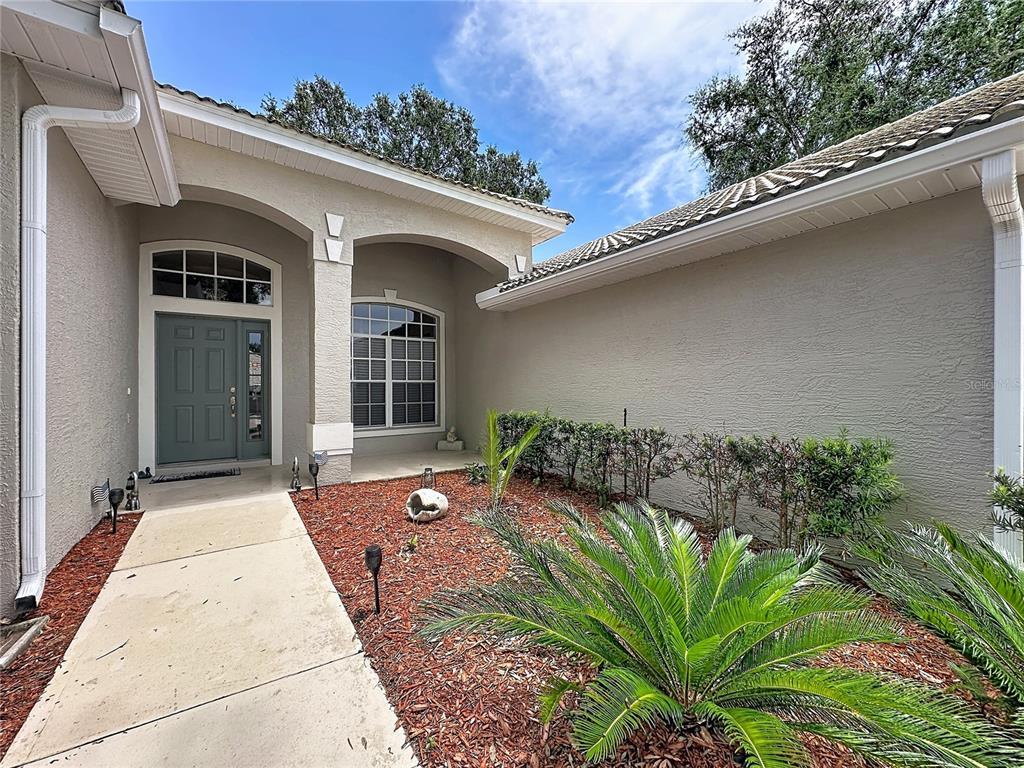 A concrete walkway leads to the front entrance of a house with a landscaped yard — 2112 SAINT IVES COURT, CLERMONT, FL