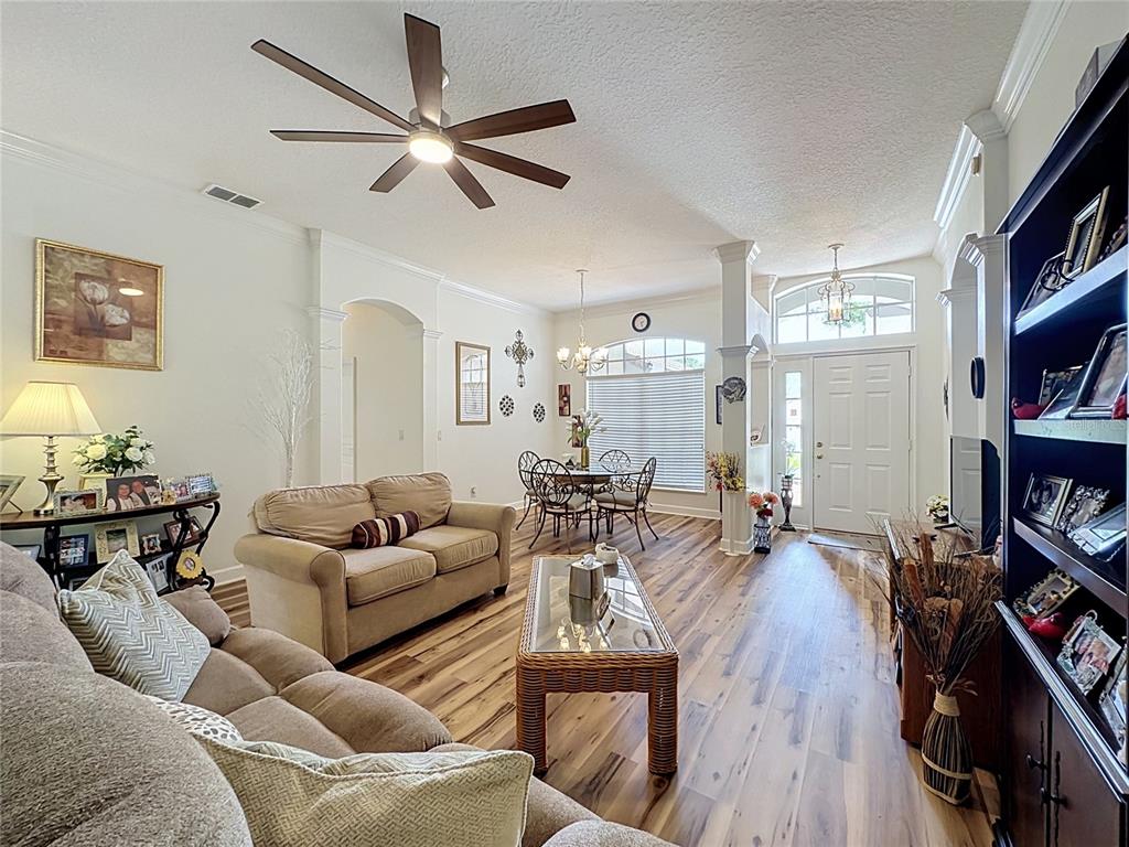 A living room and dining area feature wood-look flooring, a ceiling fan, and a front door — 2112 SAINT IVES COURT, CLERMONT, FL