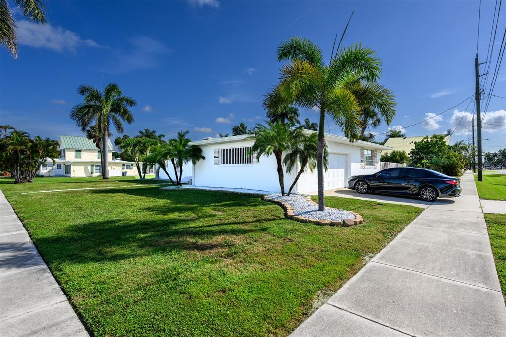 A white single-story house with a palm tree in the front yard and a car — 330 HARVEY STREET, PUNTA GORDA, FL