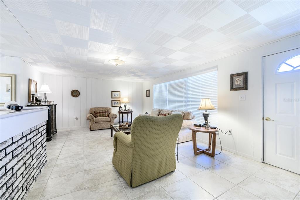 A living room features white tiled floors, a textured ceiling, and a brick fireplace — 330 HARVEY STREET, PUNTA GORDA, FL