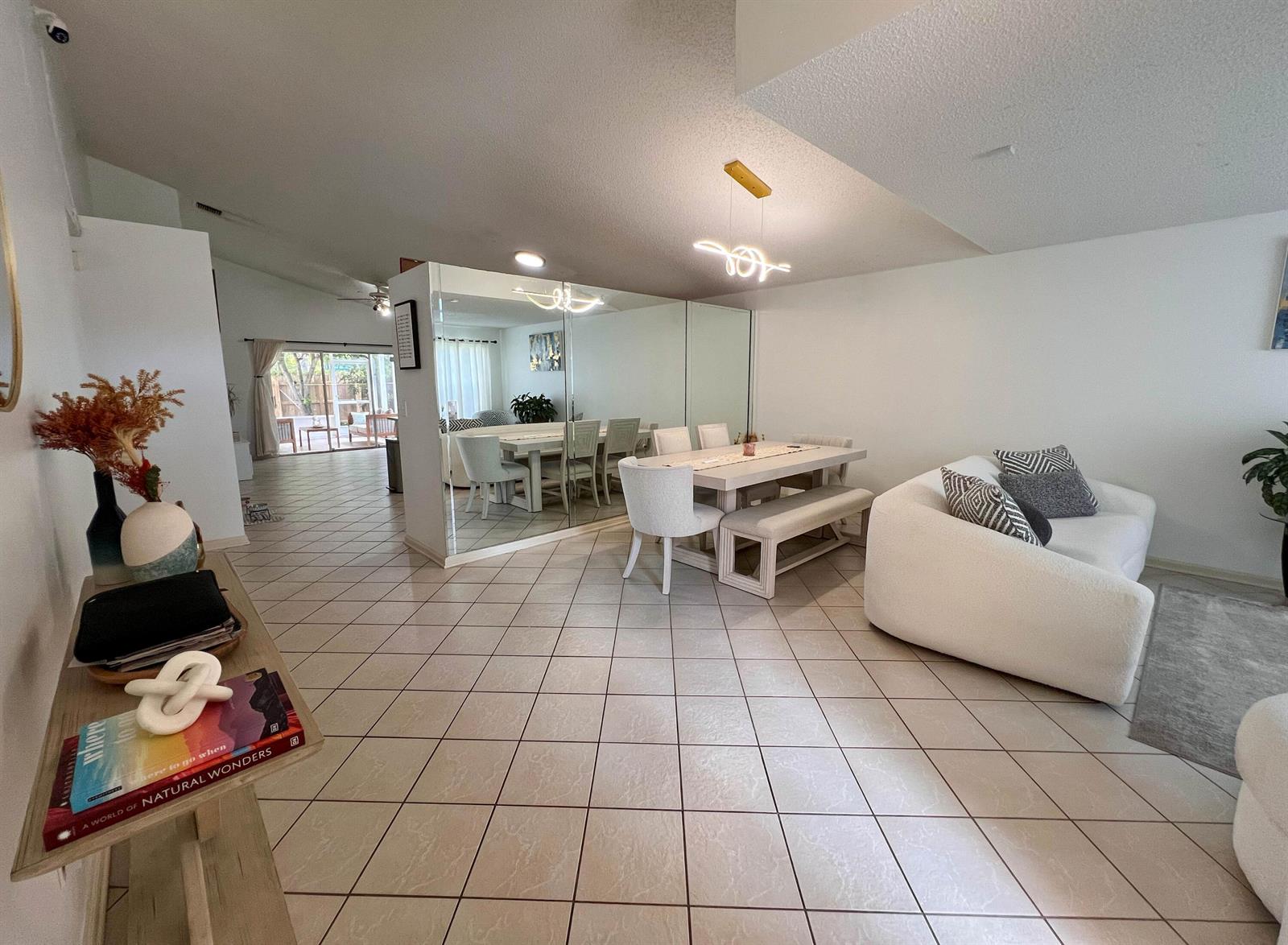 A dining area with a mirrored wall, white furniture, and tile flooring in an open space — 8229 White Rock Circle, Boynton Beach FL 33436, BOYNTON BEACH, FL