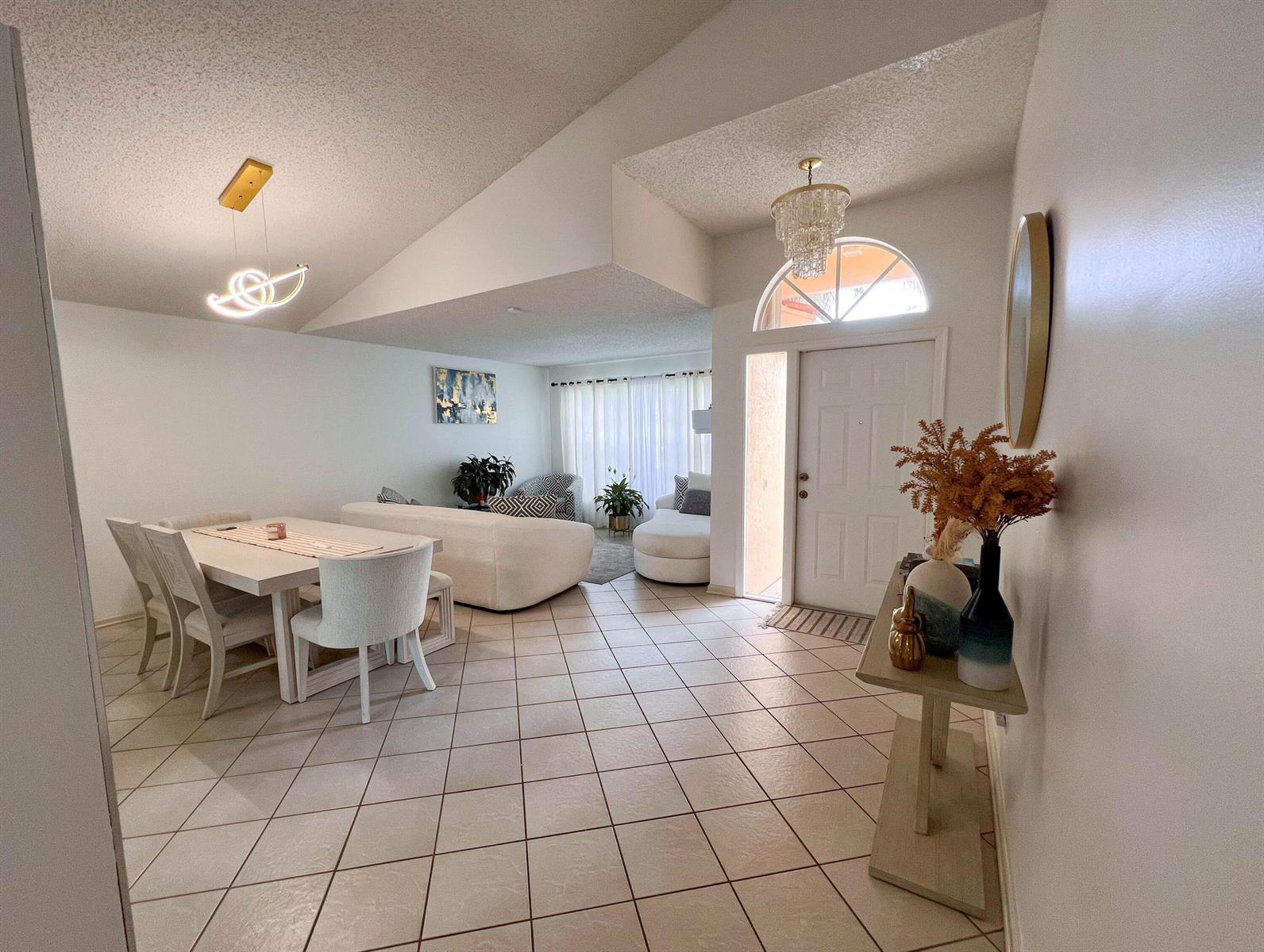 A bright open-concept living and dining area features tiled floors, vaulted ceilings, and a foyer — 8229 White Rock Circle, Boynton Beach FL 33436, BOYNTON BEACH, FL