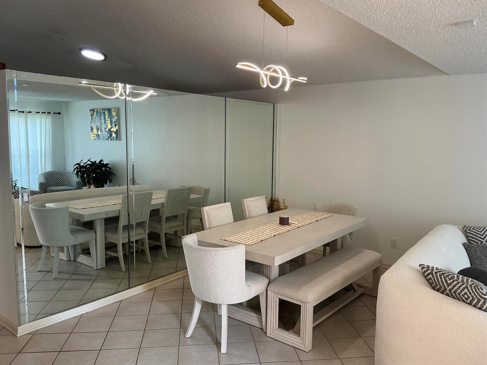 A dining room with a light-colored table, chairs, bench, and a large mirrored wall — 8229 White Rock Circle, Boynton Beach FL 33436, BOYNTON BEACH, FL