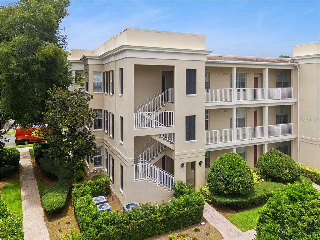 An exterior view of a three-story apartment building with white staircases and balconies — 844 BLUE SAGE STREET UNIT 101, CELEBRATION, FL