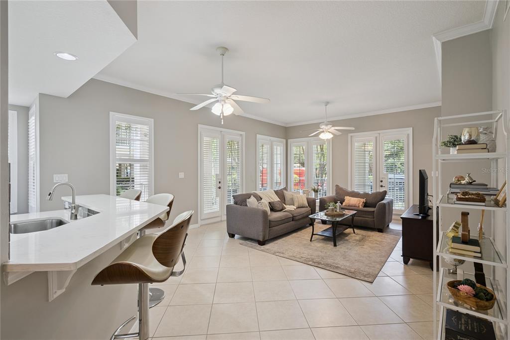 A living room with tile floors, two ceiling fans, and a kitchen island with barstools — 844 BLUE SAGE STREET UNIT 101, CELEBRATION, FL