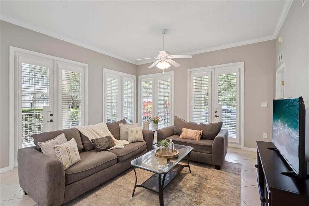 A living room features a gray sofa and loveseat, glass coffee table, and glass doors — 844 BLUE SAGE STREET UNIT 101, CELEBRATION, FL