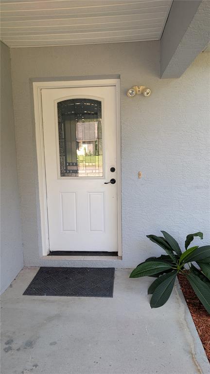 A white front door with a glass insert sits on a concrete porch next to greenery — 4023 N EAGLE NEST POINT, CRYSTAL RIVER, FL